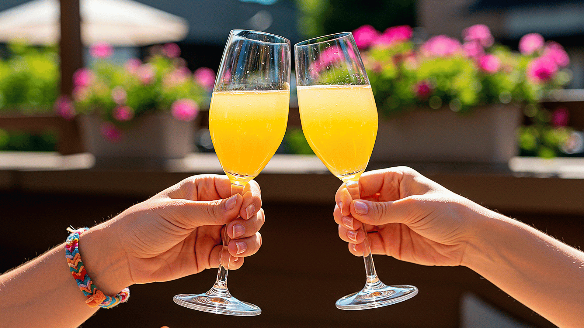 An image of two hands cheering with mimosas